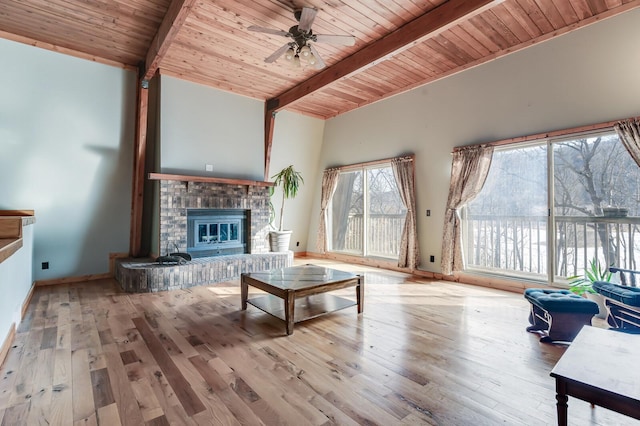 living room with a ceiling fan, lofted ceiling with beams, hardwood / wood-style flooring, wood ceiling, and a brick fireplace