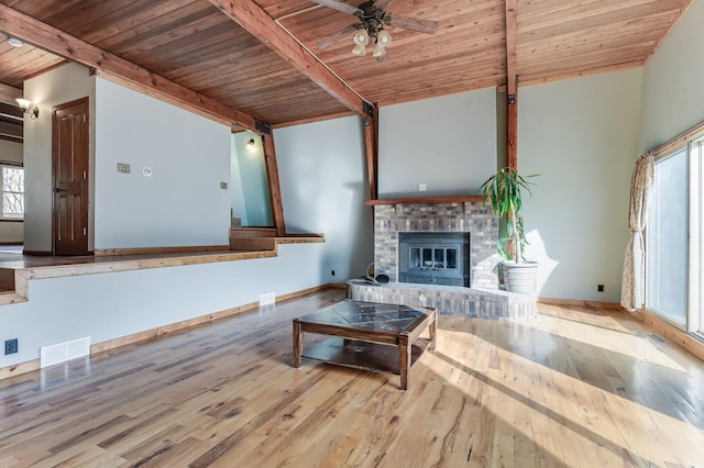 living room featuring a brick fireplace, visible vents, hardwood / wood-style flooring, baseboards, and wood ceiling