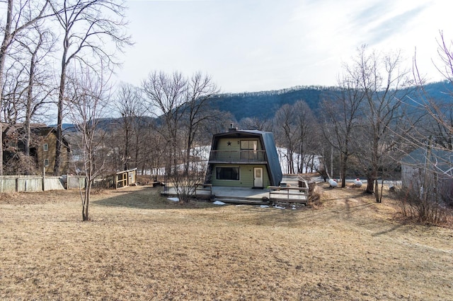 back of property with a gambrel roof, a deck with mountain view, and a balcony