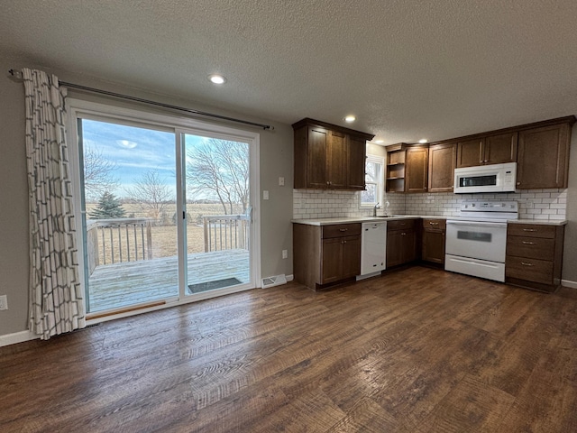 kitchen featuring a sink, open shelves, backsplash, dark wood finished floors, and white appliances