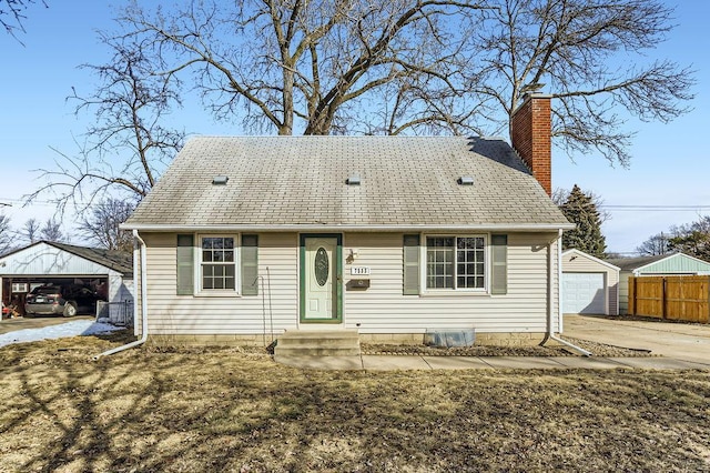 view of front facade featuring fence, roof with shingles, an outdoor structure, a garage, and a chimney