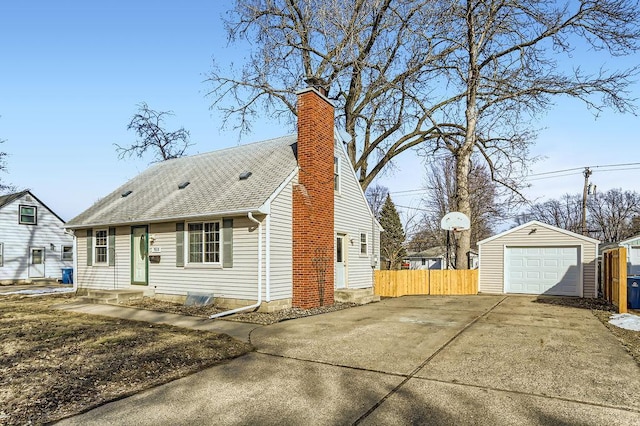 view of front of home with fence, concrete driveway, a chimney, a garage, and an outbuilding