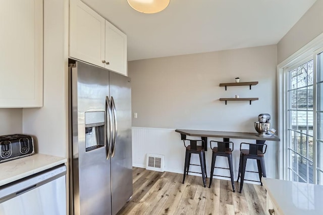 kitchen with visible vents, light wood-style floors, white cabinets, stainless steel appliances, and open shelves