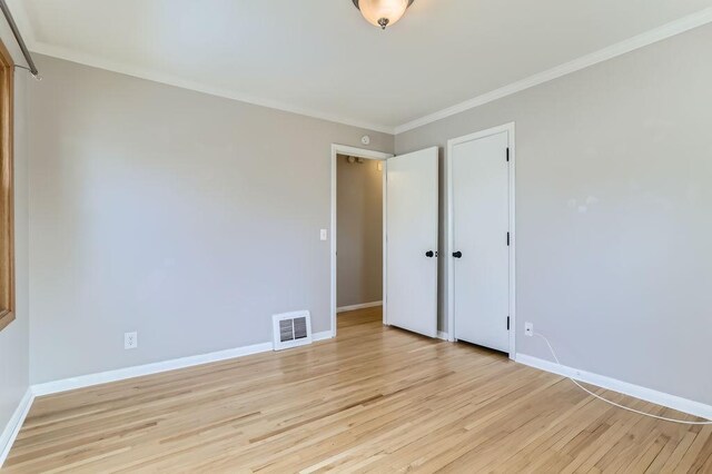 unfurnished bedroom with crown molding, baseboards, visible vents, and light wood finished floors