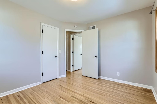 unfurnished bedroom with light wood-style flooring, visible vents, and baseboards