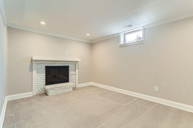 interior space featuring visible vents, ornamental molding, a glass covered fireplace, carpet floors, and baseboards