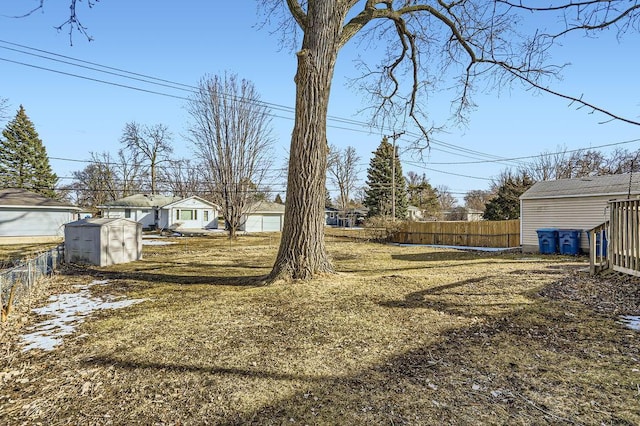 view of yard featuring an outbuilding, a storage shed, and fence