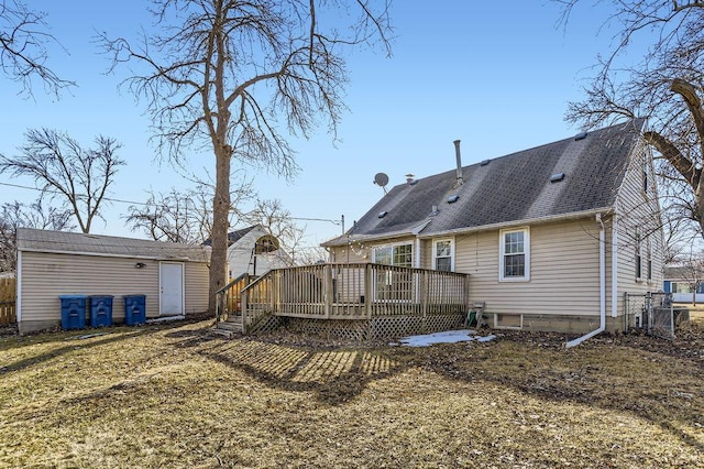 back of property featuring an outdoor structure, a deck, and roof with shingles