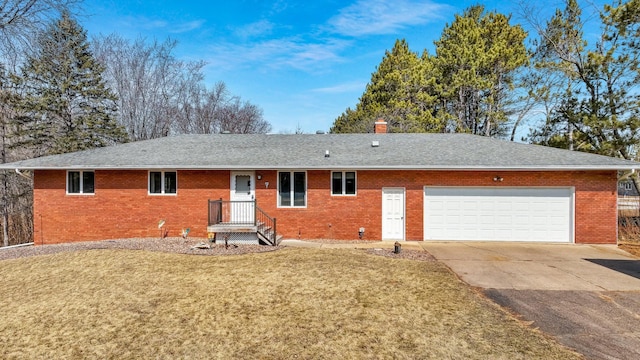 rear view of house featuring brick siding, a chimney, a garage, a yard, and driveway