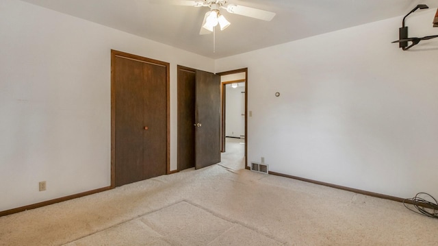 unfurnished bedroom with baseboards, light colored carpet, visible vents, and multiple closets