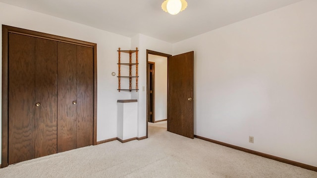 unfurnished bedroom featuring light colored carpet, baseboards, and a closet