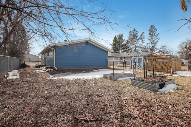 rear view of house with an outbuilding, a vegetable garden, and fence