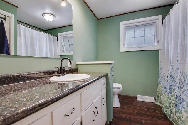 full bath featuring vanity, visible vents, wood tiled floor, crown molding, and toilet