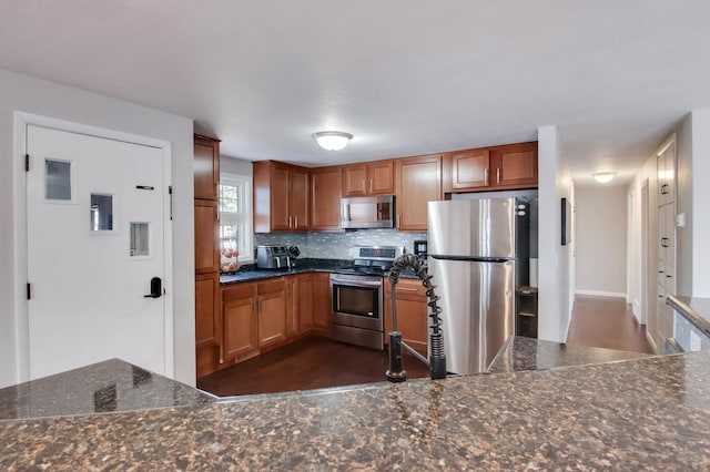 kitchen featuring stainless steel appliances, tasteful backsplash, dark wood finished floors, and brown cabinetry