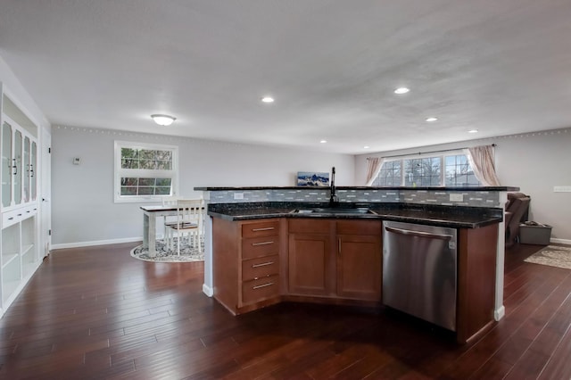 kitchen with a sink, dishwasher, dark wood finished floors, and dark stone countertops