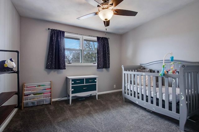 carpeted bedroom with baseboards, a crib, and ceiling fan