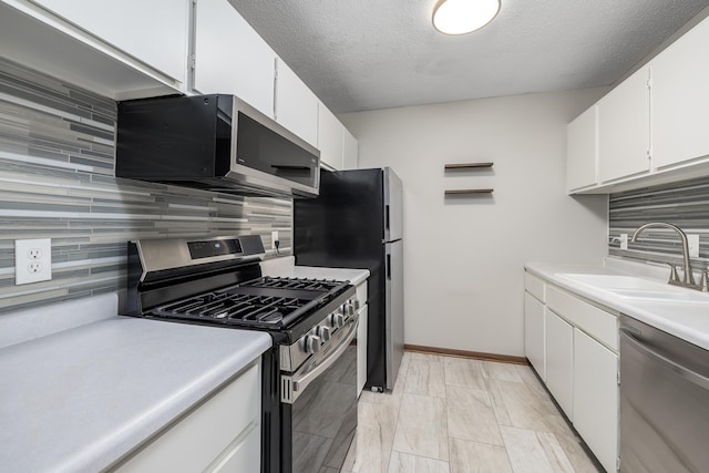 kitchen with a sink, stainless steel appliances, light countertops, white cabinets, and tasteful backsplash