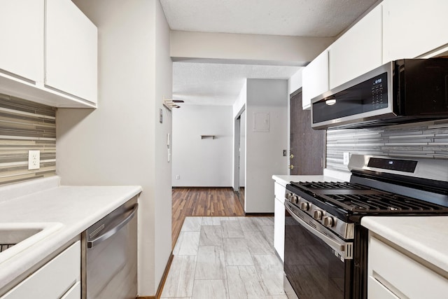 kitchen featuring a textured ceiling, tasteful backsplash, appliances with stainless steel finishes, white cabinets, and light countertops