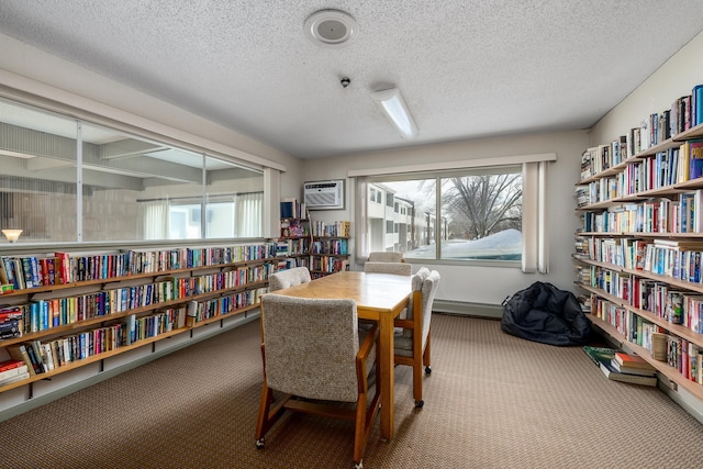 interior space featuring carpet flooring, a textured ceiling, wall of books, and a wall mounted AC