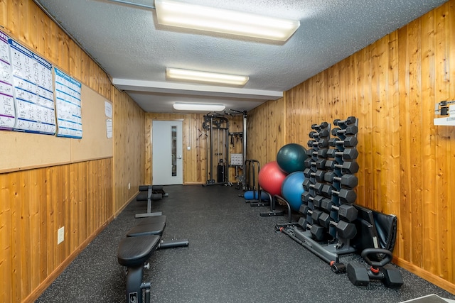 exercise area featuring wood walls and a textured ceiling