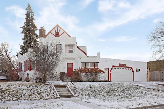 view of front of property featuring stucco siding, driveway, a chimney, and an attached garage