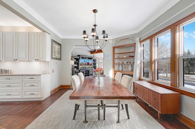 dining space featuring dark wood finished floors, a chandelier, and baseboards