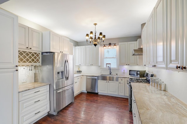 kitchen with dark wood-type flooring, decorative light fixtures, appliances with stainless steel finishes, an inviting chandelier, and a sink