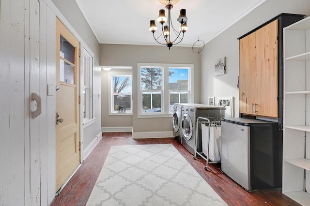 clothes washing area with a chandelier, washing machine and dryer, ornamental molding, dark wood-style floors, and cabinet space