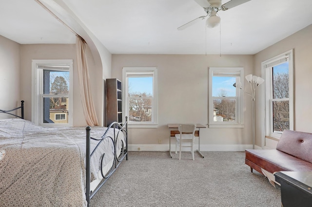 carpeted bedroom featuring baseboards, multiple windows, and ceiling fan