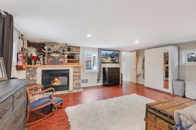 living area with wood finished floors, visible vents, baseboards, recessed lighting, and a fireplace