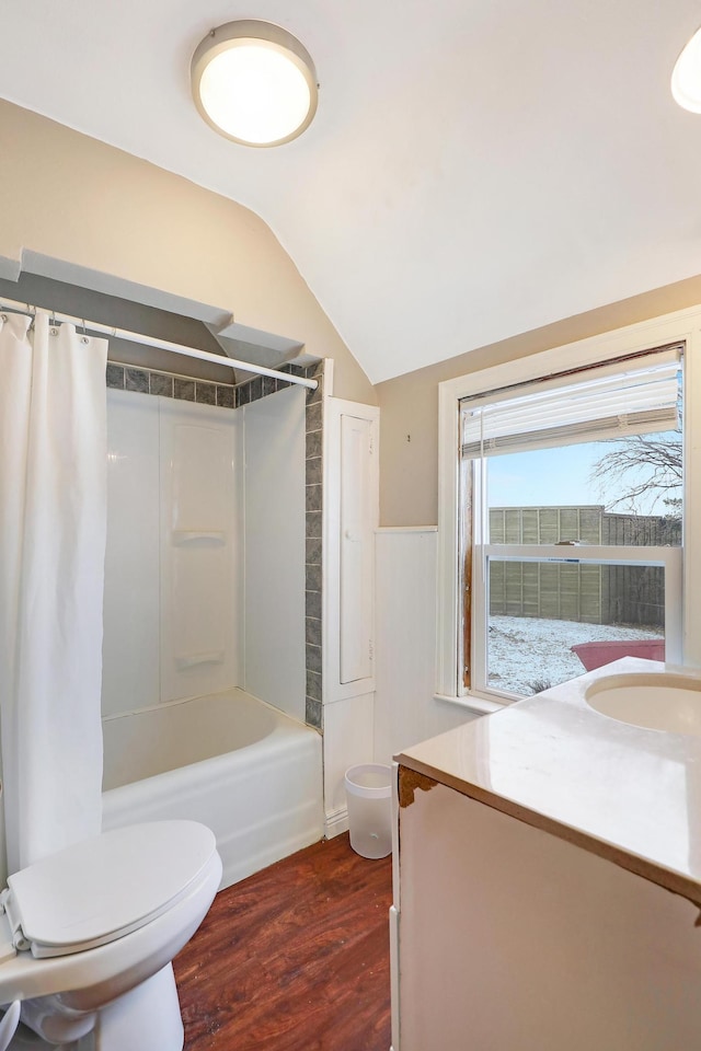 full bath featuring vanity, wood finished floors, vaulted ceiling, shower / bath combination with curtain, and toilet