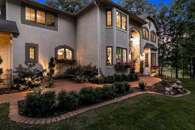 view of front facade featuring stucco siding, a front lawn, and a patio area