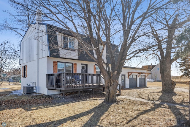 rear view of property featuring a deck, cooling unit, and a garage