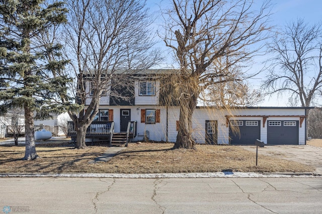 view of front facade featuring a wooden deck, driveway, and an attached garage