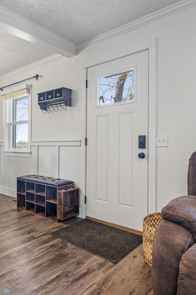 entryway featuring wood finished floors, a textured ceiling, ornamental molding, and a decorative wall