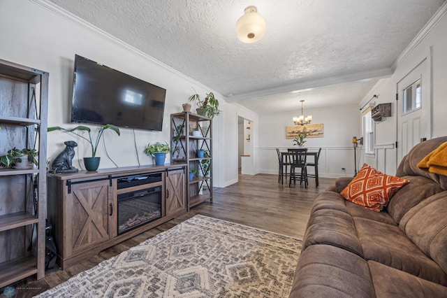 living area featuring a notable chandelier, ornamental molding, a textured ceiling, and wood finished floors