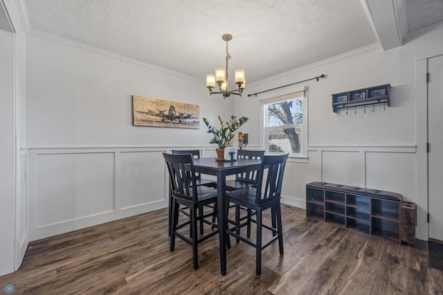 dining space featuring ornamental molding, a textured ceiling, an inviting chandelier, and wood finished floors