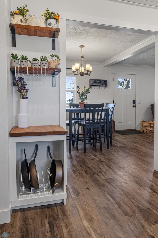 dining space featuring crown molding, a notable chandelier, wood finished floors, and a textured ceiling