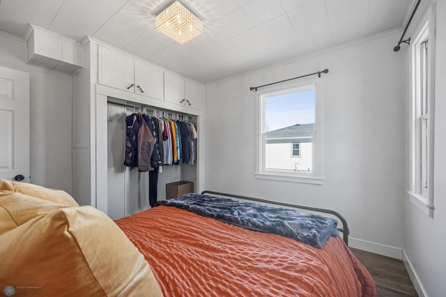 bedroom featuring crown molding, baseboards, dark wood-style flooring, and a closet