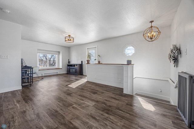 unfurnished living room with a baseboard heating unit, baseboards, an inviting chandelier, and wood finished floors