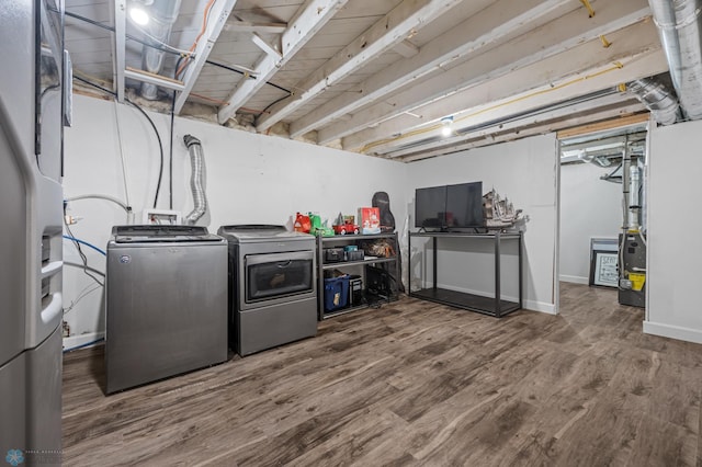 washroom featuring laundry area, washing machine and dryer, baseboards, and wood finished floors