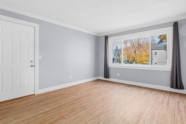 spare room with a textured ceiling, baseboards, light wood finished floors, and ornamental molding