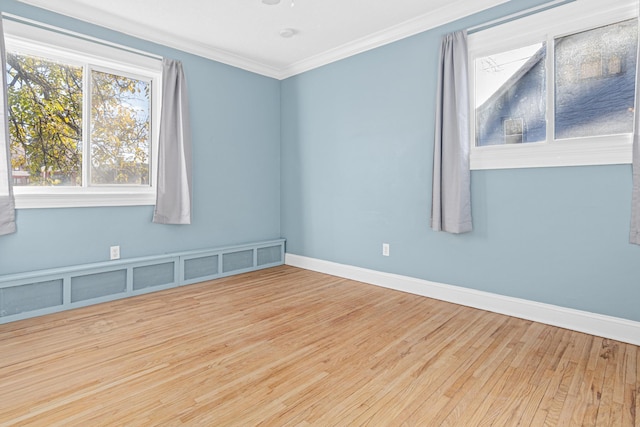 spare room featuring crown molding, baseboards, and wood finished floors