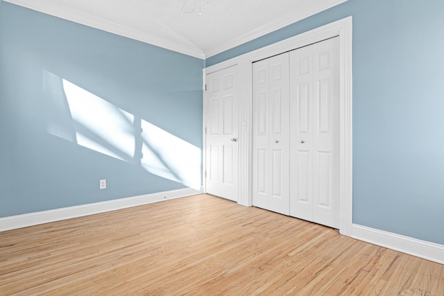 unfurnished bedroom with a ceiling fan, wood finished floors, baseboards, lofted ceiling, and crown molding