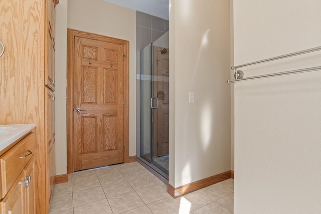 full bath featuring tile patterned flooring, a shower stall, vanity, and baseboards