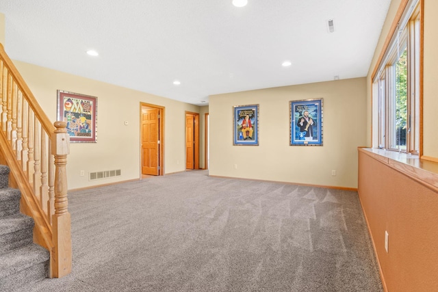 carpeted empty room with recessed lighting, visible vents, baseboards, and stairway