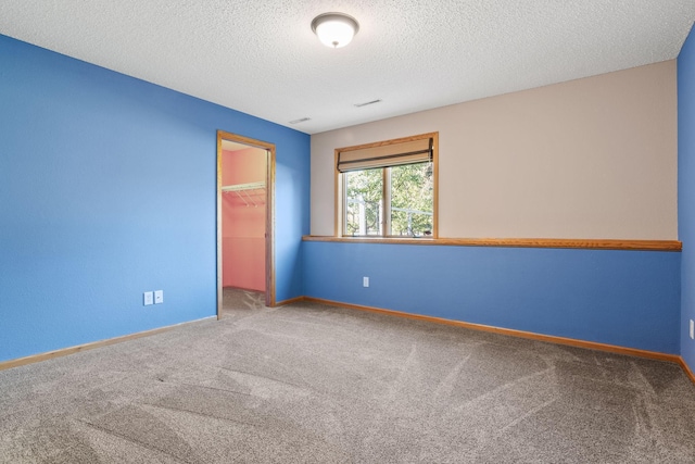 carpeted spare room featuring baseboards and a textured ceiling