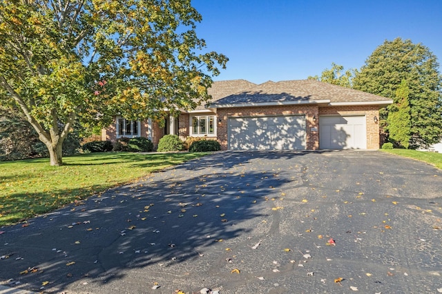 view of front of property with aphalt driveway, a garage, brick siding, and a front yard