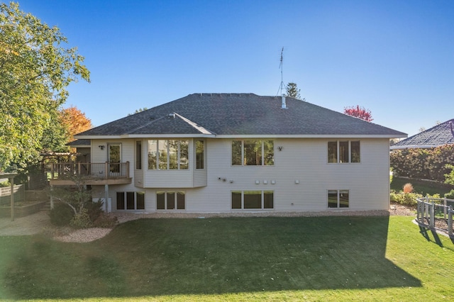 back of house with a wooden deck, a yard, and a shingled roof