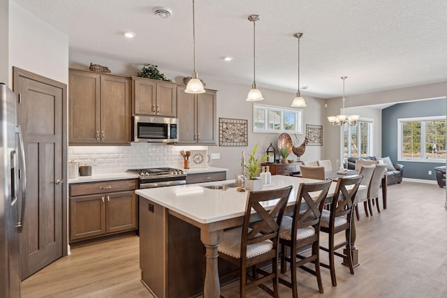 kitchen with light countertops, decorative backsplash, light wood-style flooring, a kitchen breakfast bar, and stainless steel appliances